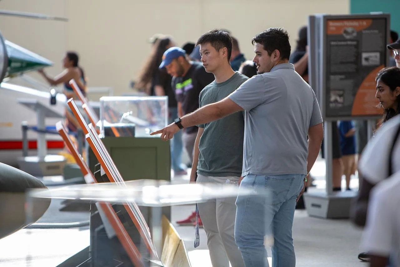 Visitors lean over an interactive exhibit table in the Museum of Flight galleries